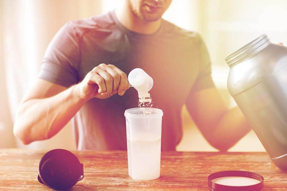 A man filling protein powder into a shaker.