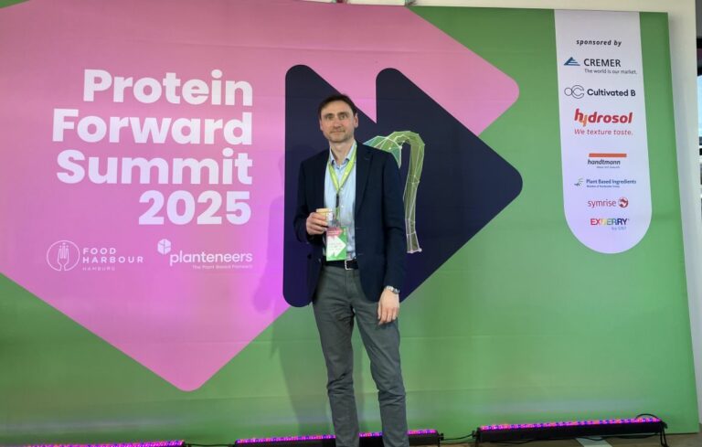 Dr. Waldemar Buxmann standing in front of the welcome banner of the Protein Forward Summit.